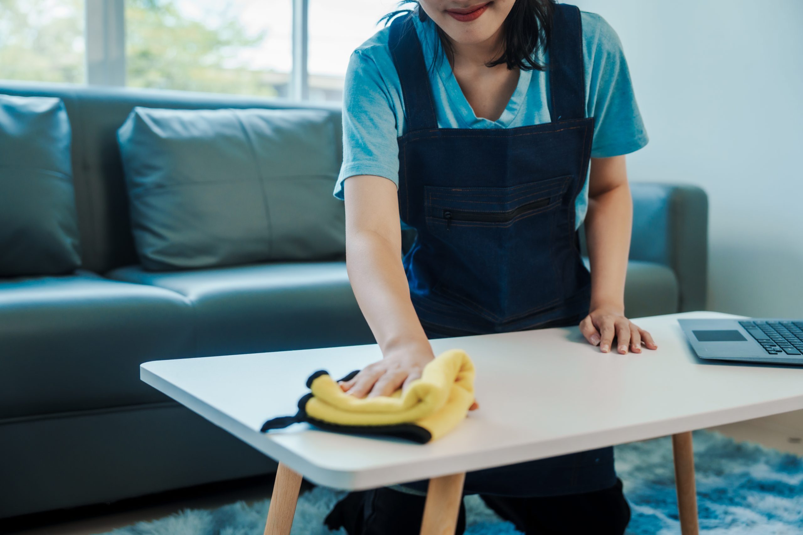 Cleans floor and desk. Hand of asian chinese woman wiping work desk, close-up.